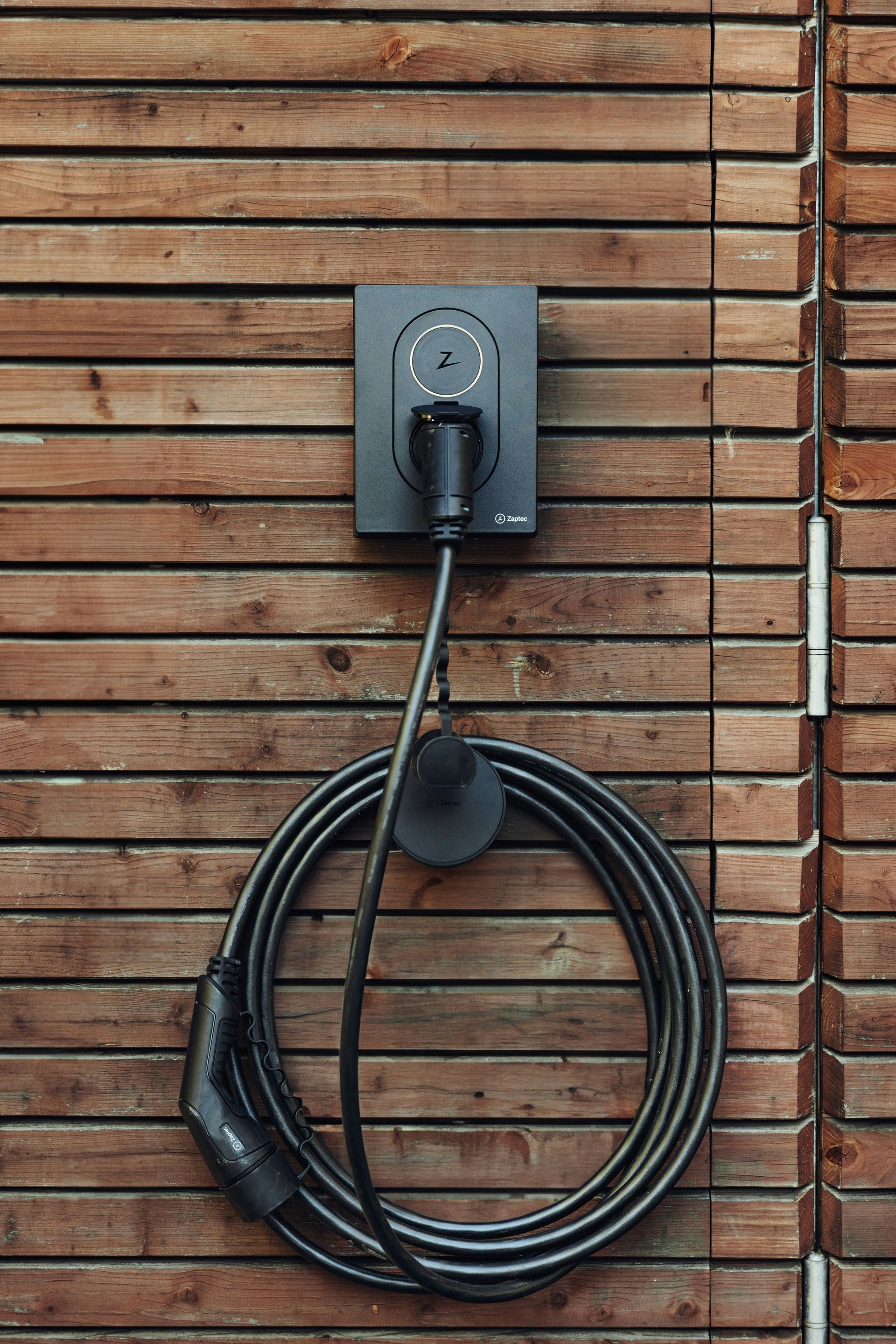a black cord plugged into a wooden wall